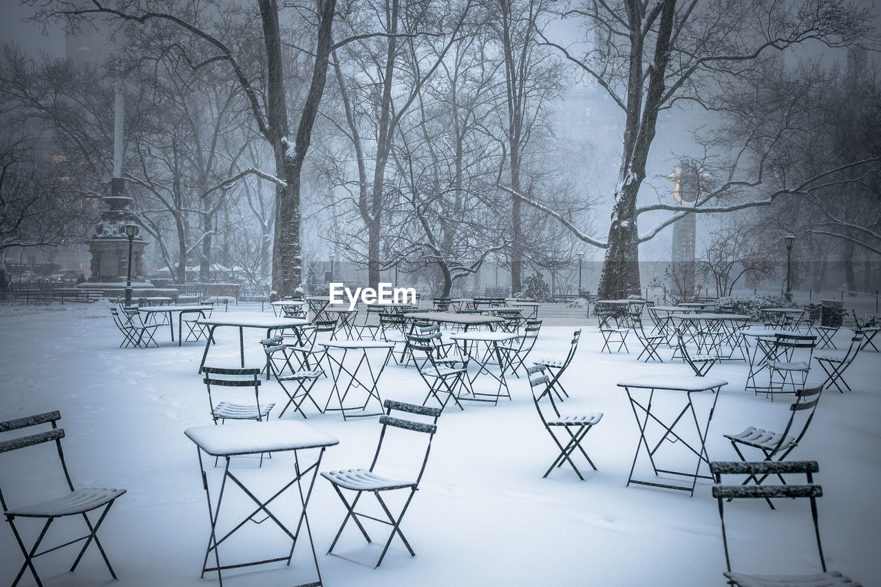 Snow covered tables and chairs in park