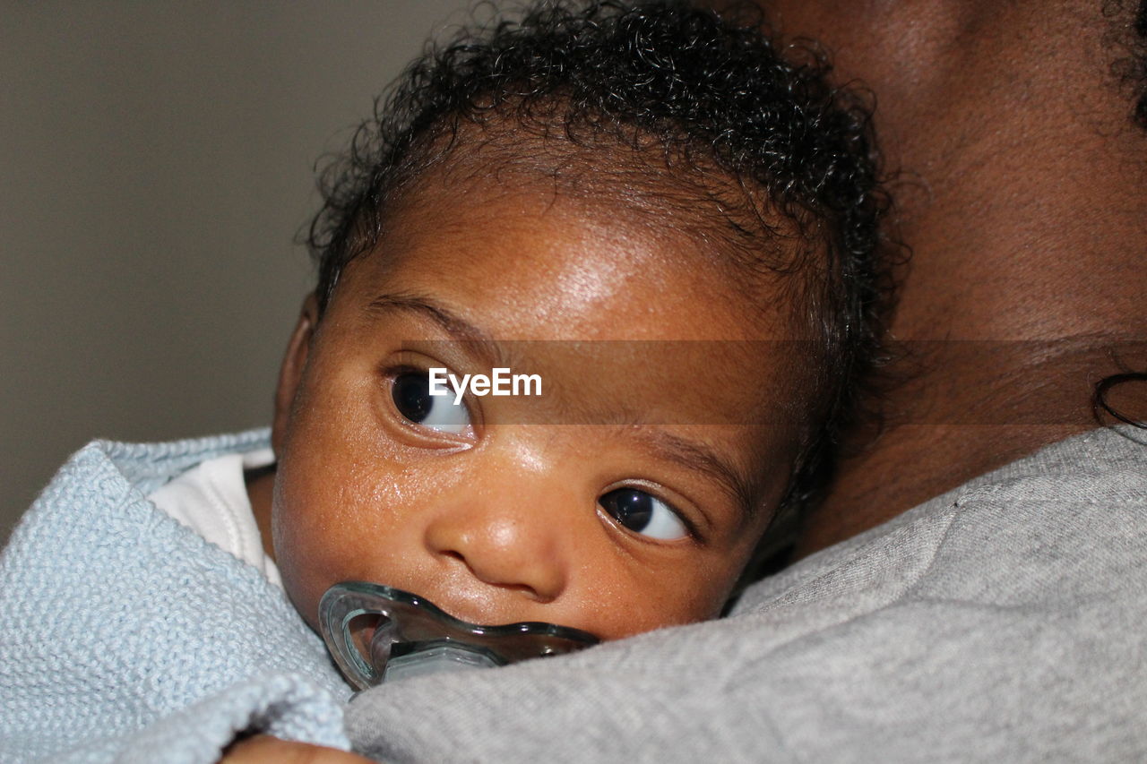 Close-up portrait of cute baby relaxing on mother's shoulder 