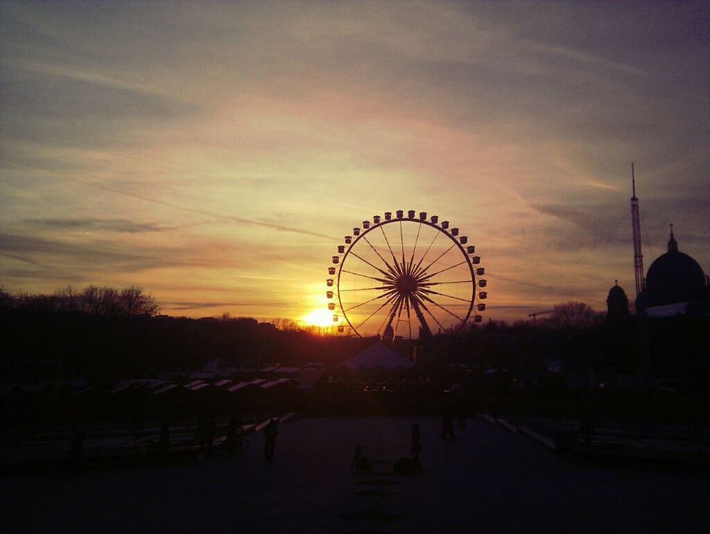 Silhouette ferris wheel at amusement park during sunset