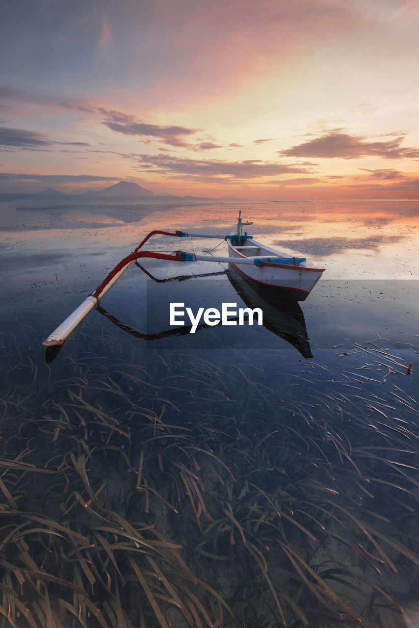 Boat moored on sea against sky during sunset