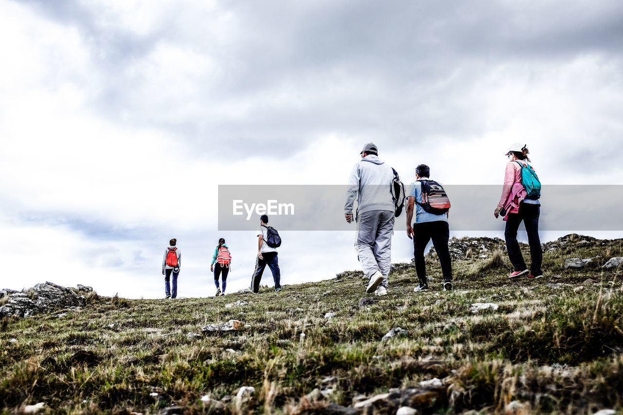 Rear view of people walking on land against sky