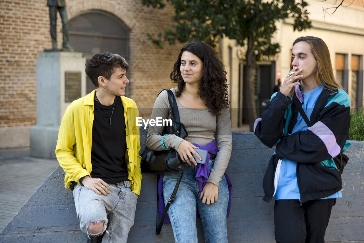 Friends talking while standing outdoors on the street.