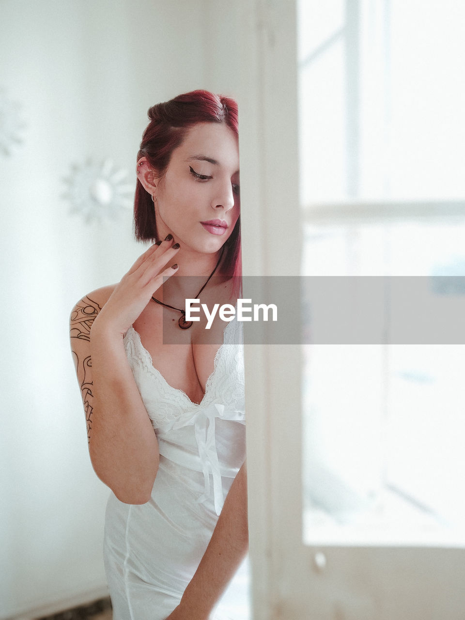 Portrait of young woman standing against window