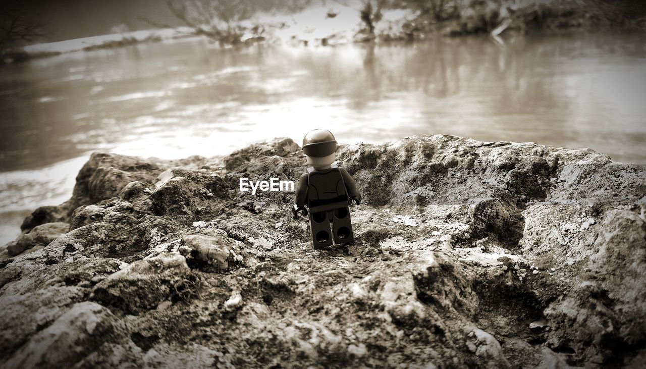 REAR VIEW OF MAN LOOKING AT ROCK FORMATION