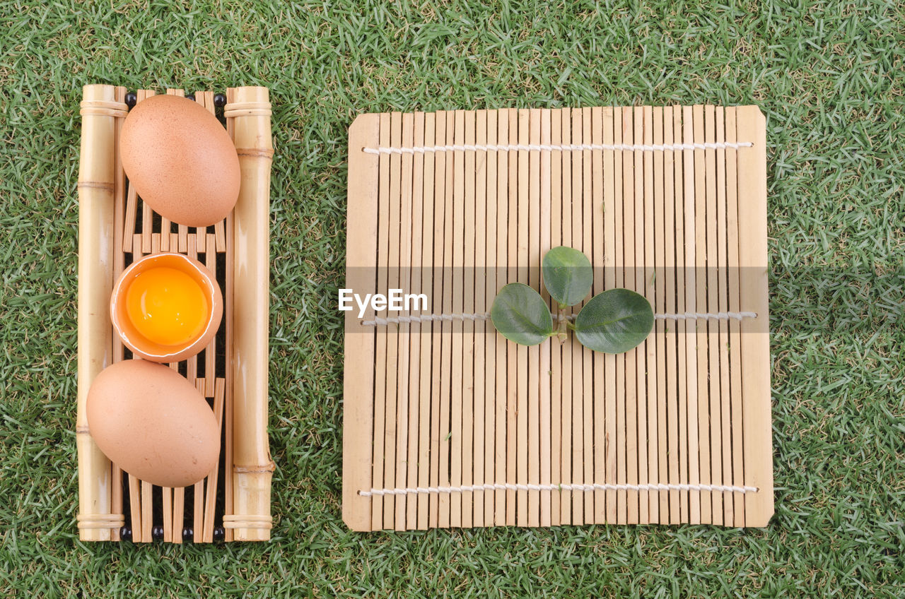 Directly above shot of egg in spoon on bamboo mat over grass