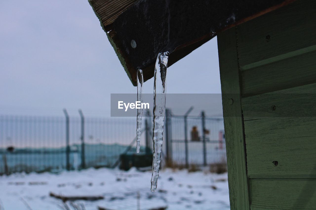 CLOSE-UP OF ICICLES ON ROOF DURING WINTER