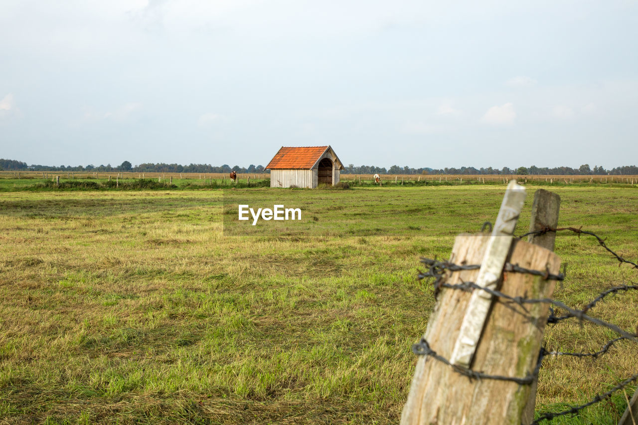 Wooden house on field against sky