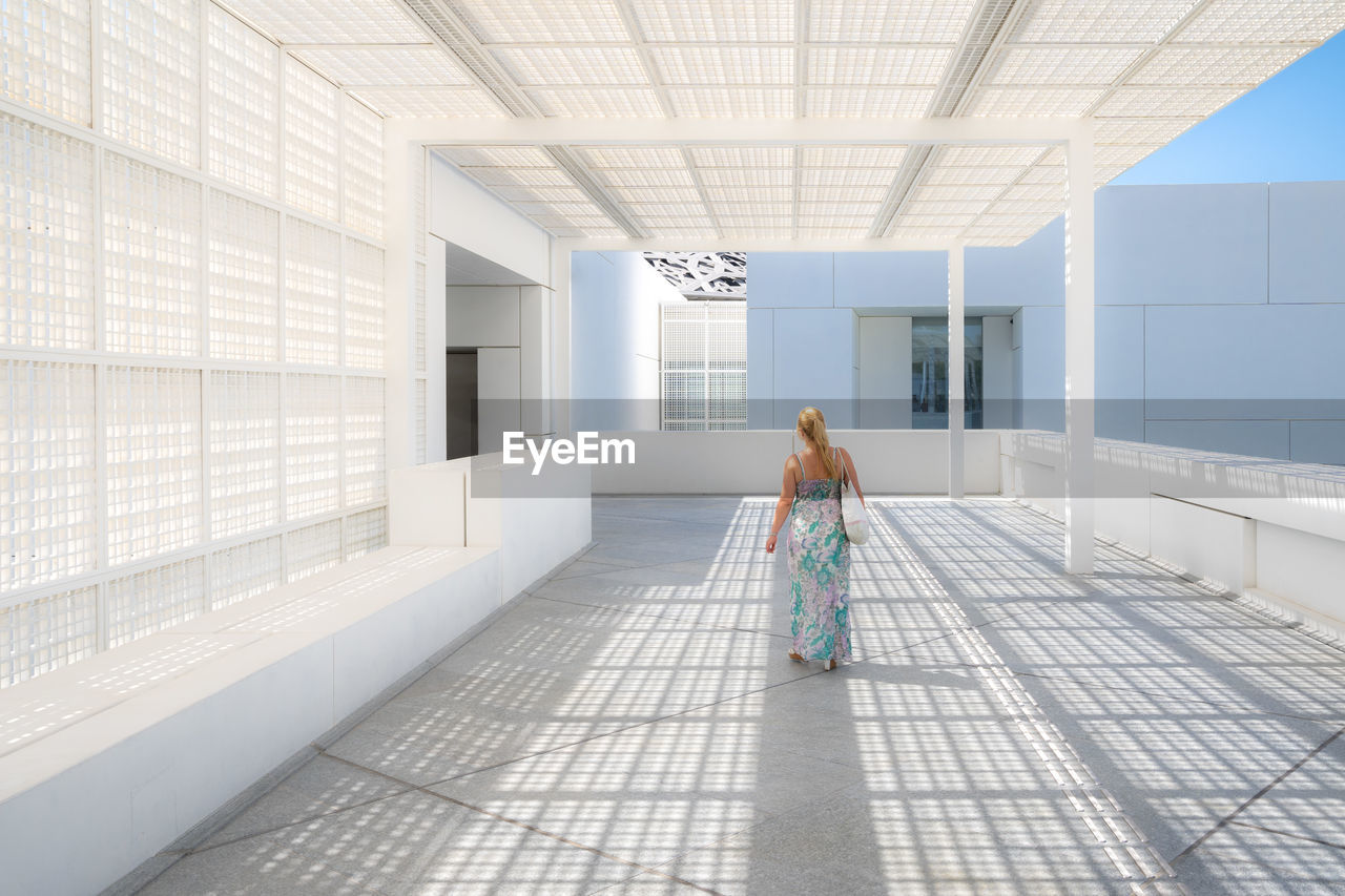 REAR VIEW OF WOMAN WALKING ON TILED FLOOR