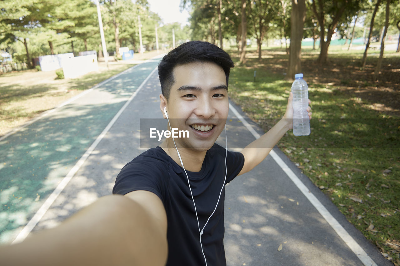 Portrait of smiling young man against trees