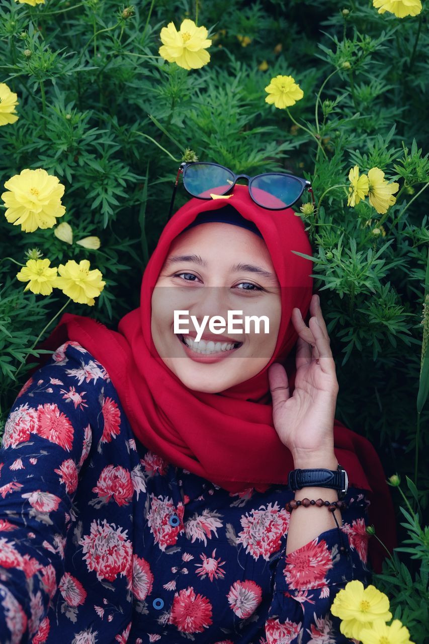 The happy smile of the girl who is among the blooming flowers
