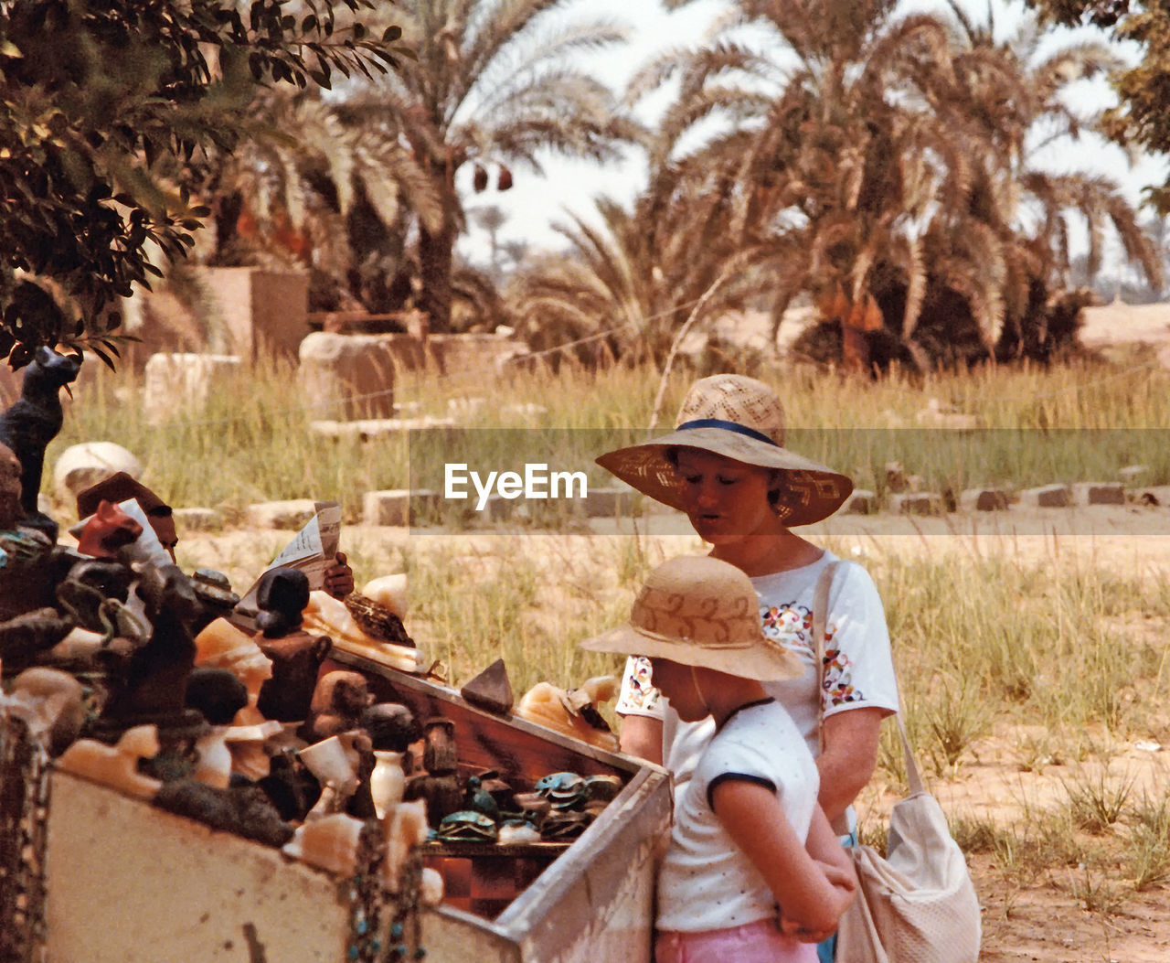 Mother standing with daughter by souvenirs on field