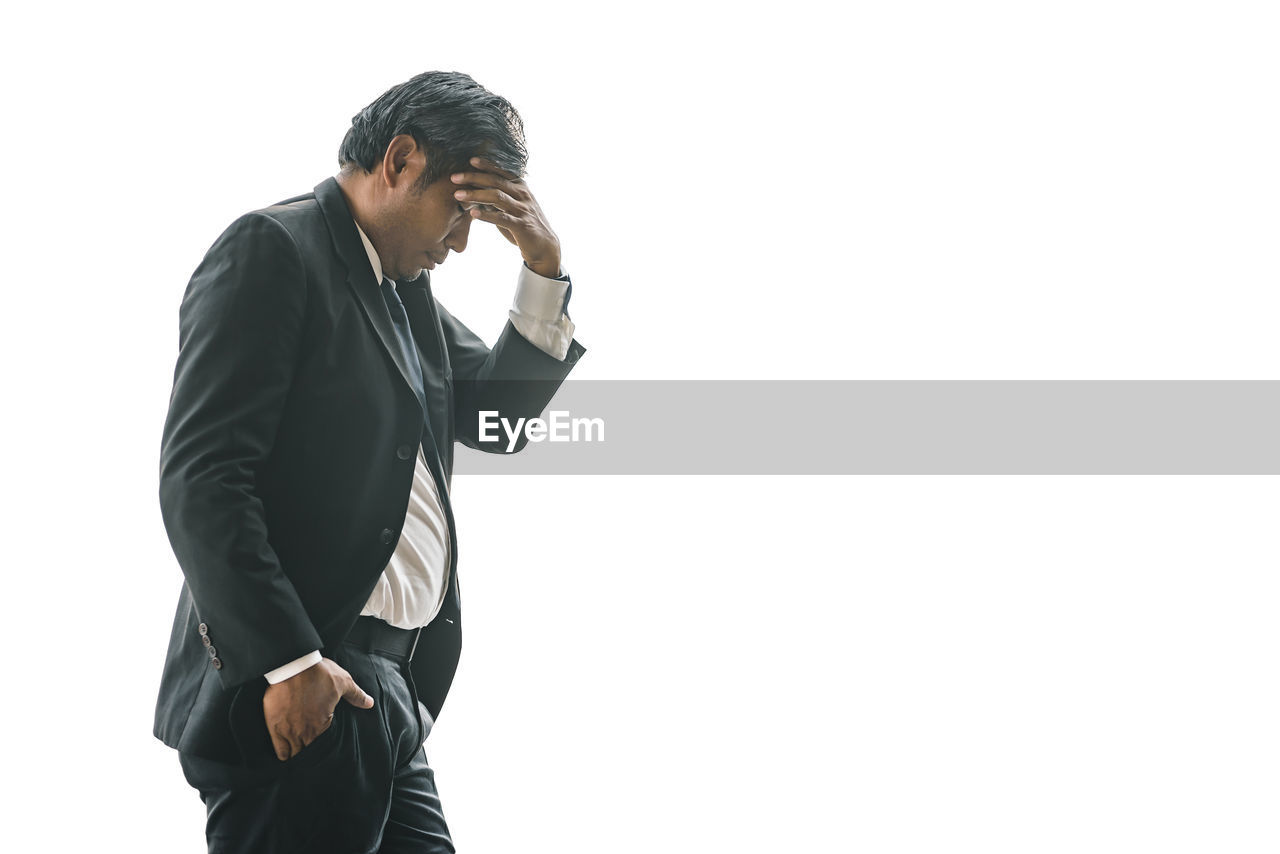 An elderly business man is worried and stressed about his problem on a white isolated background.