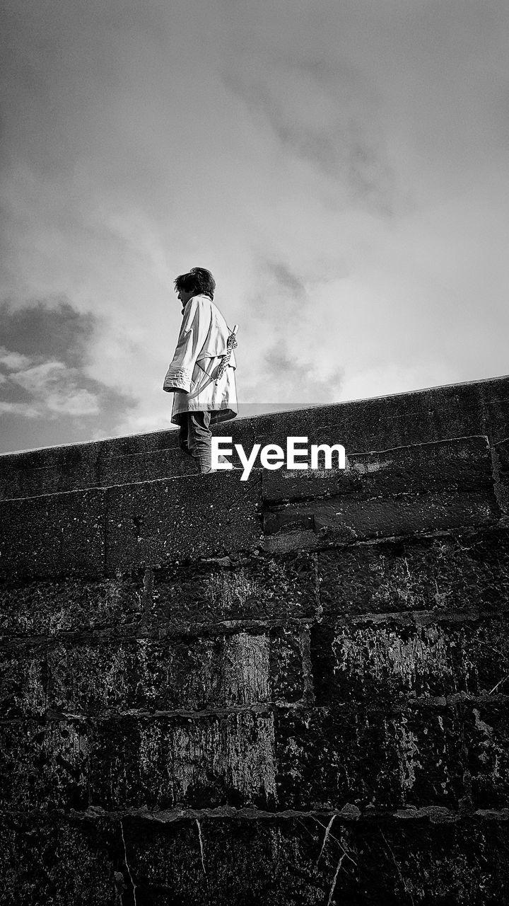 LOW ANGLE VIEW OF CHILD STANDING ON WALL