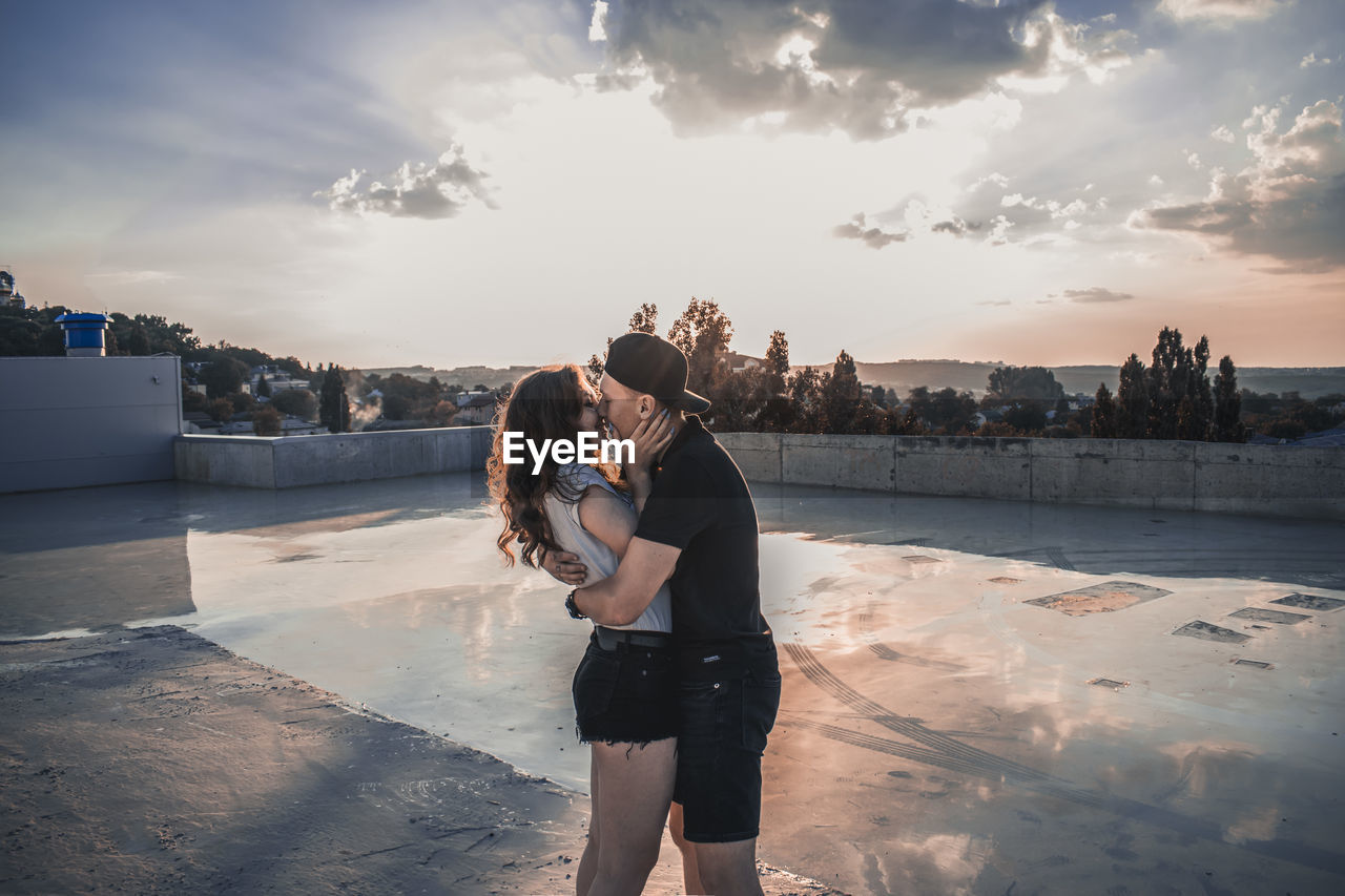 Couple kissing at poolside during sunset