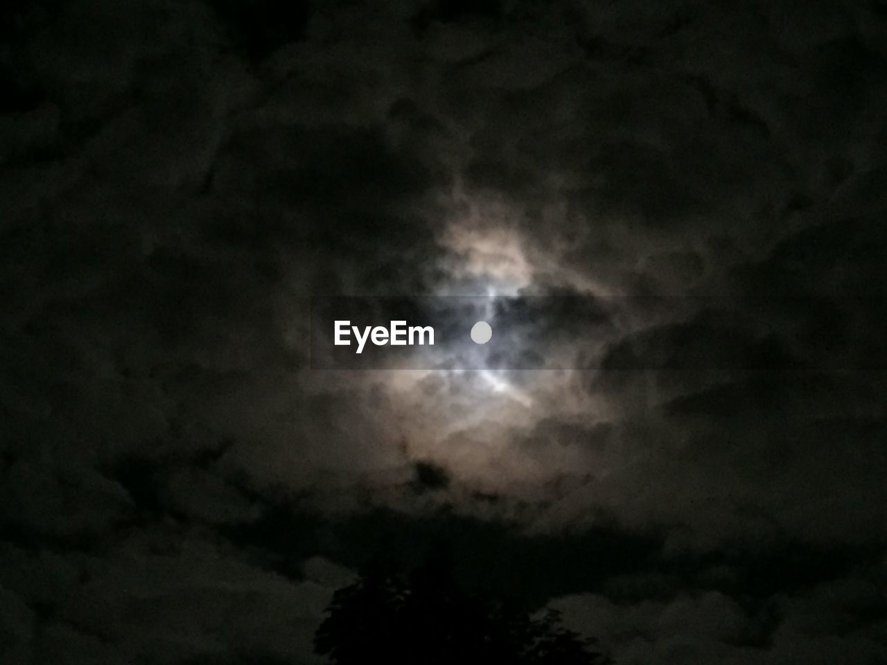 LOW ANGLE VIEW OF MOON AGAINST CLOUDY SKY