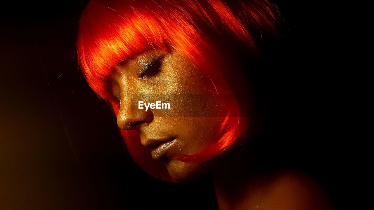 Close-up of woman with golden make-up against black background