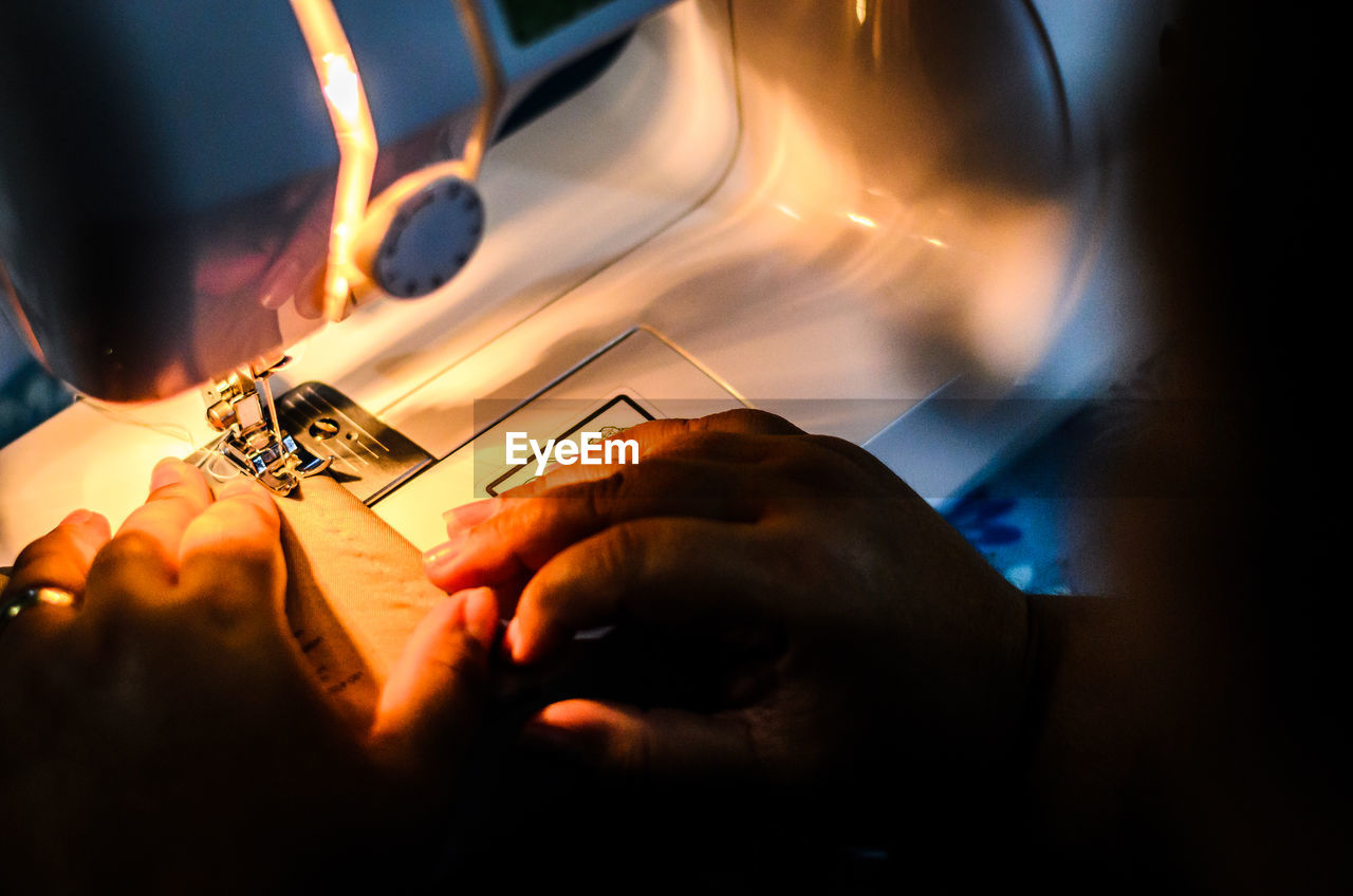 Cropped image of woman sewing in darkroom