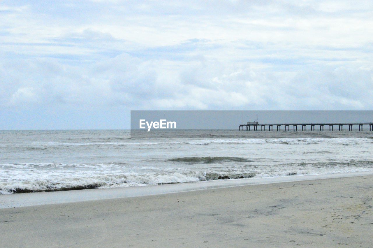 Scenic view of beach against cloudy sky