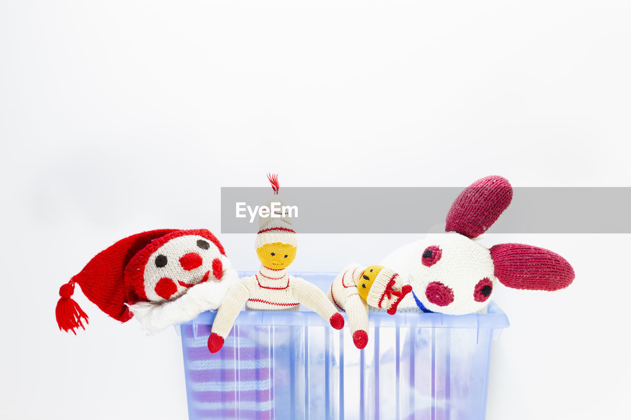 Close-up of knitted toys in container over gray background