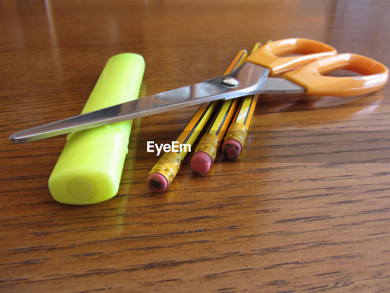 Close-up of scissor and pencils on wooden table