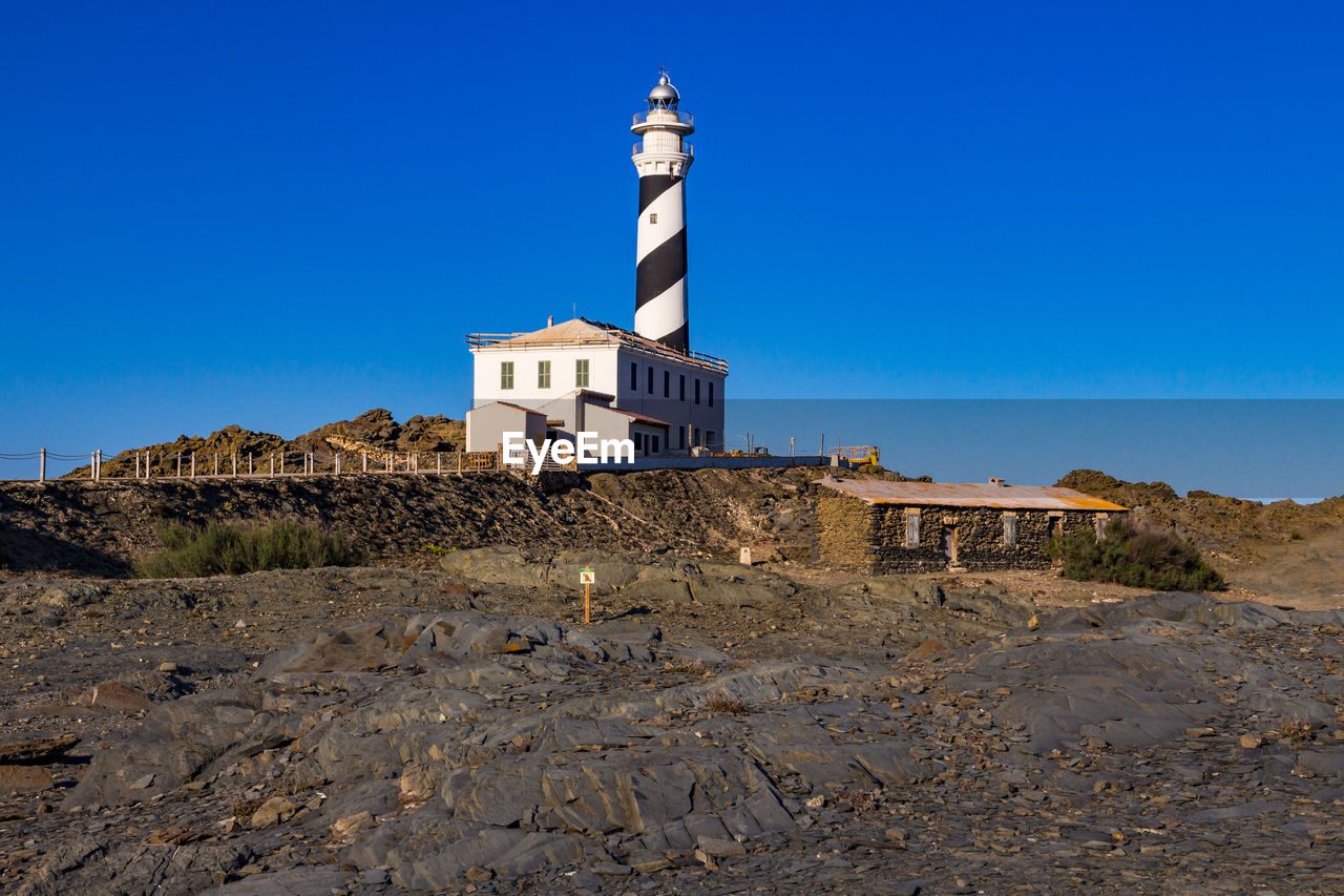 The far de favaritx lighthouse, painted black and white in a spiral, menorca island, baleares, spain