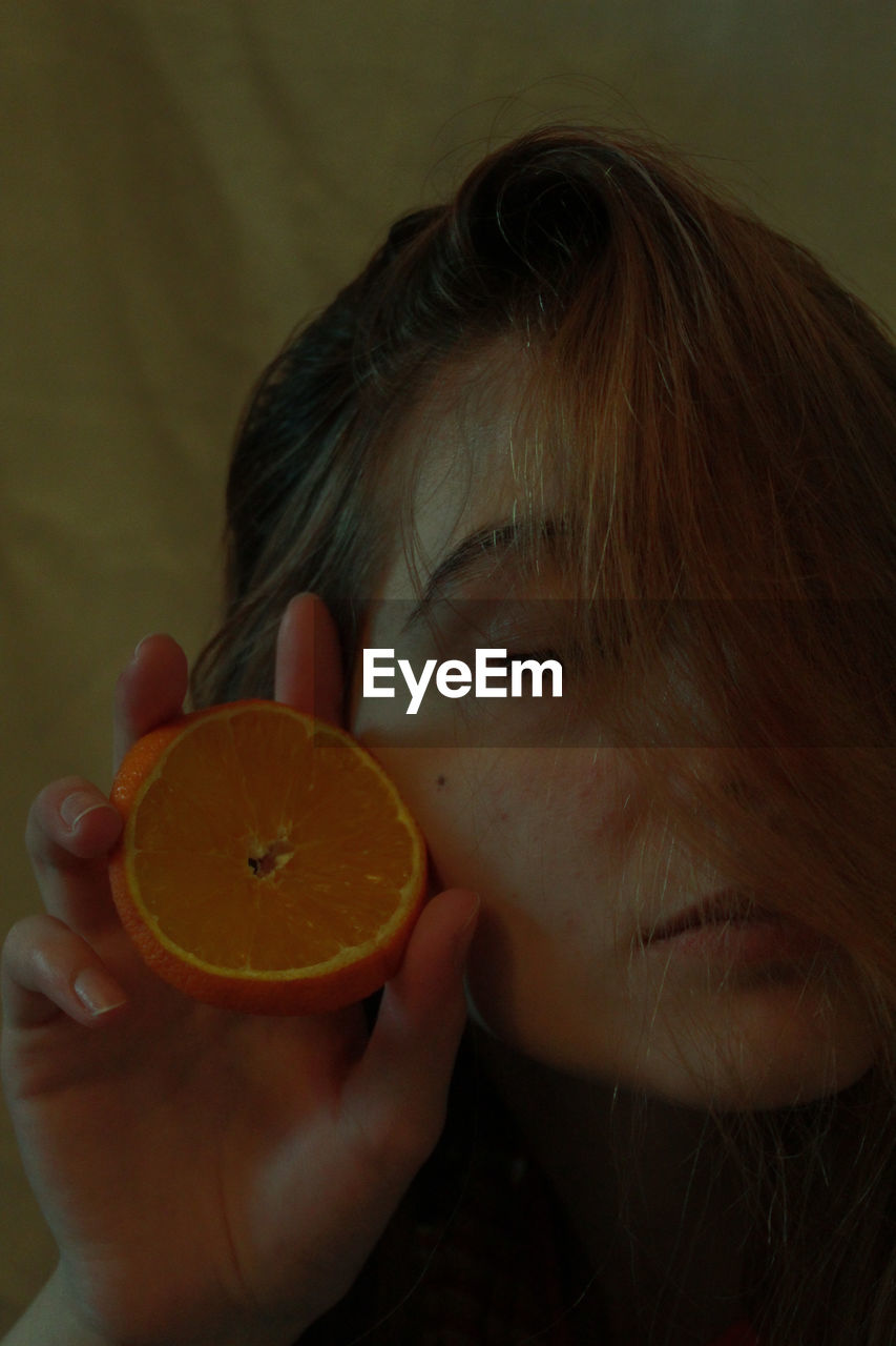 Close-up of teenage girl holding orange