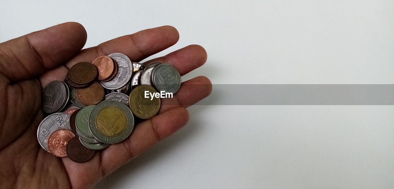 CROPPED IMAGE OF HAND HOLDING COIN