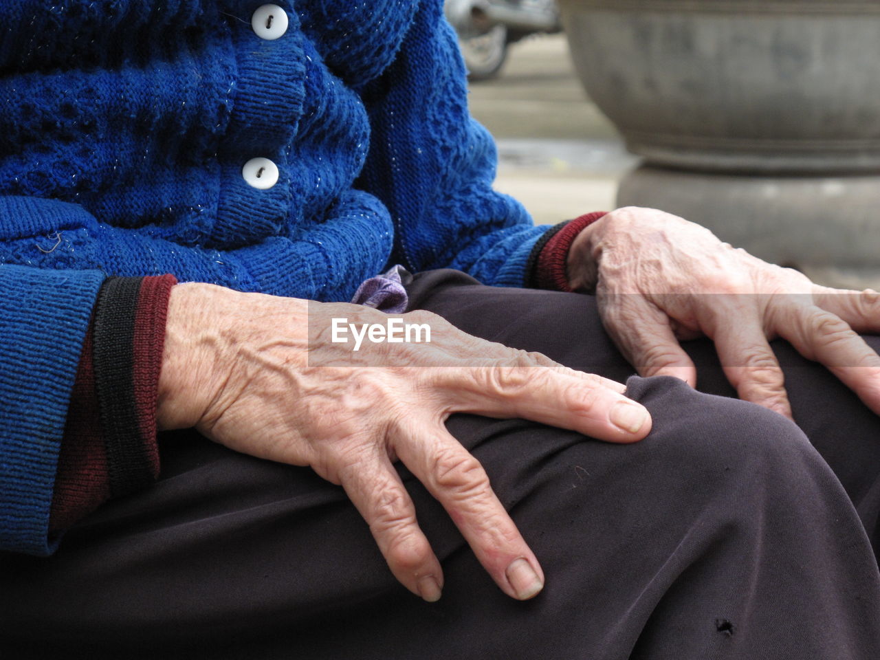 Midsection of senior woman sitting outdoors