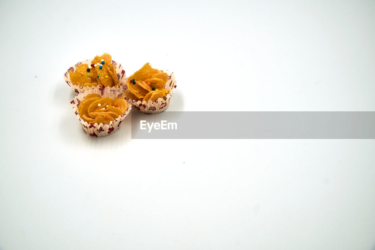 Honey cornflakes cookies in a cup over white background