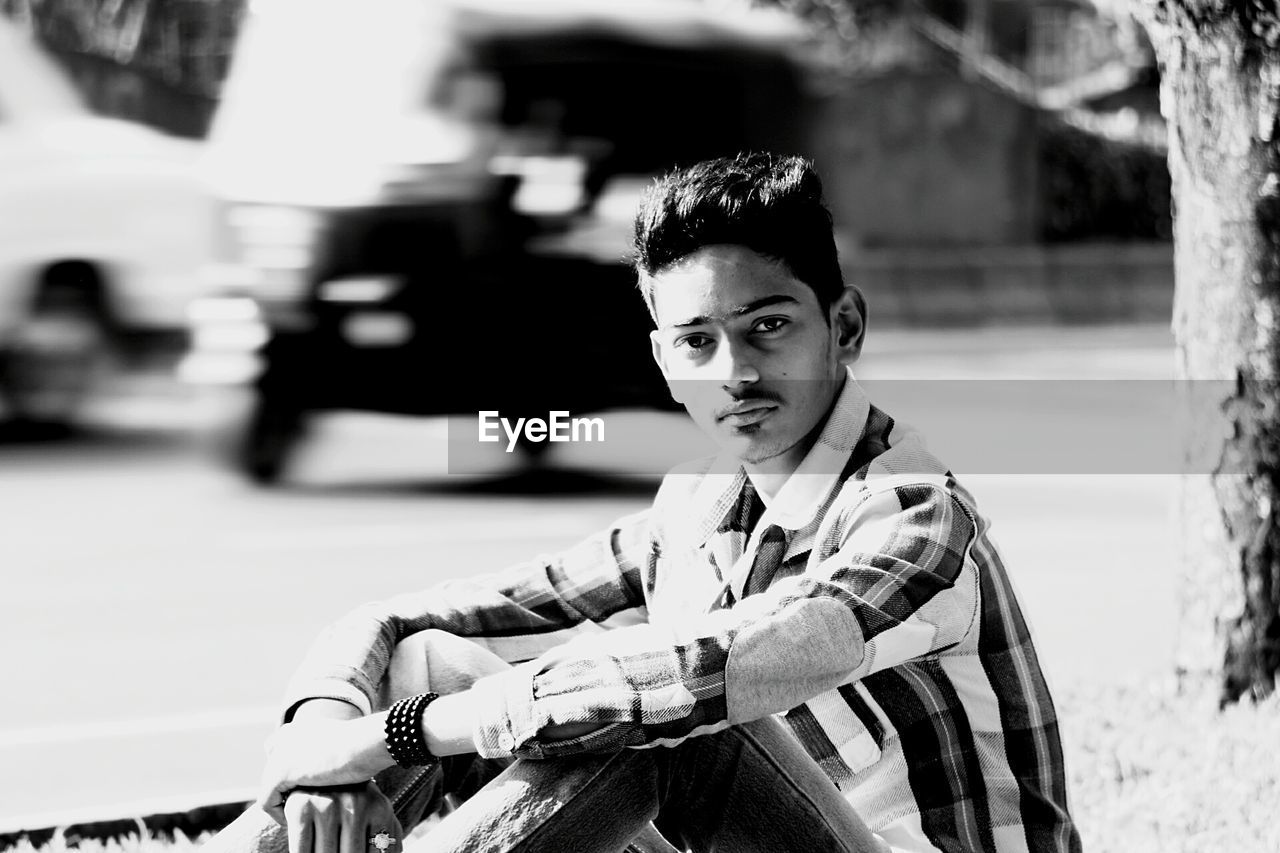 Portrait of teenager sitting on roadside