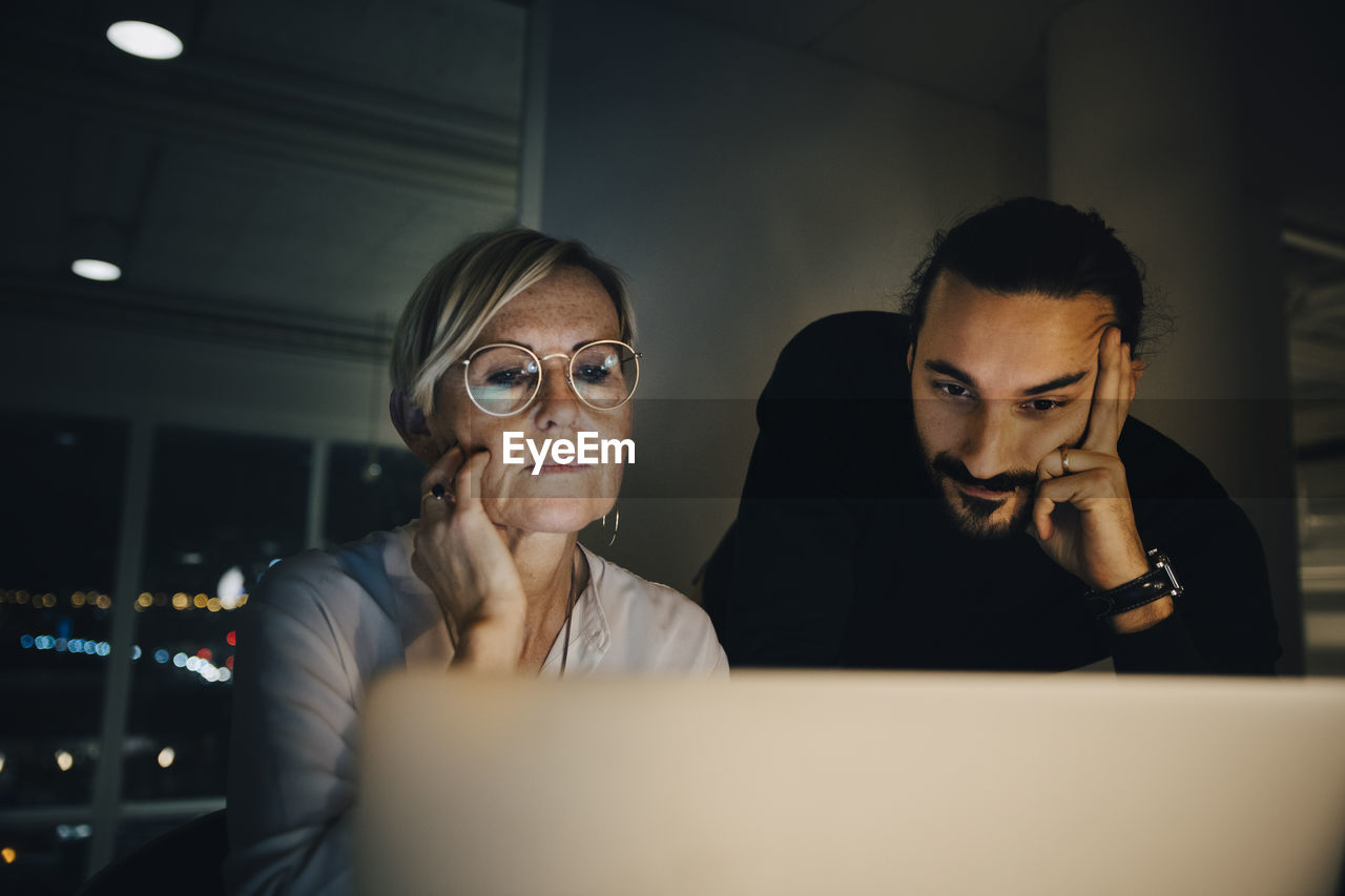 Multi-ethnic colleagues staring at laptop during meeting in office