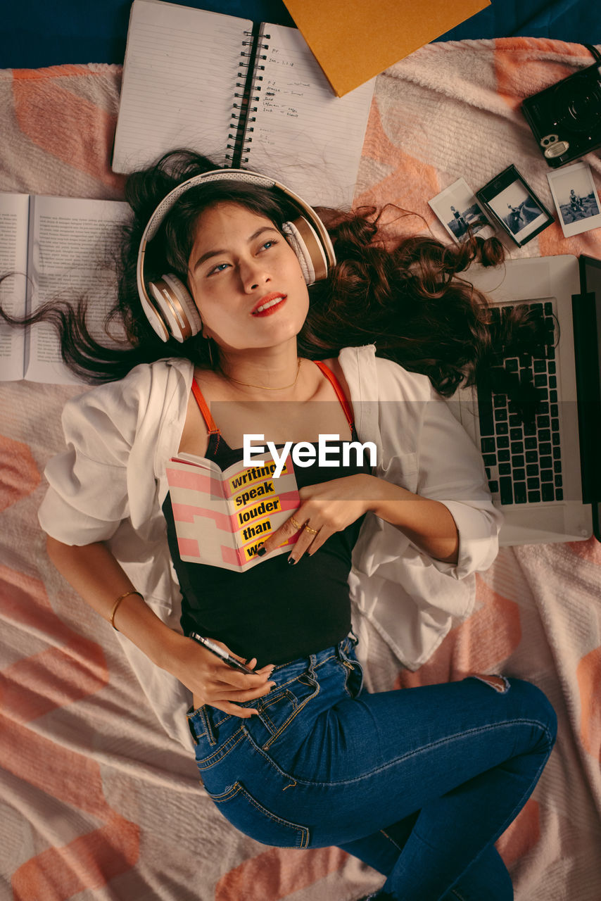 Portrait of a smiling young woman lying on bed at home