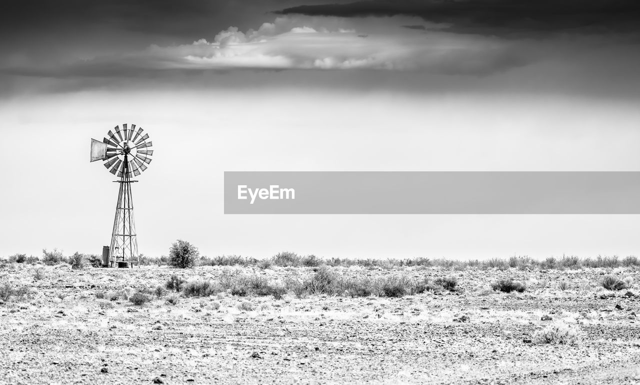 Black and white photo of a windmill in an acrid landscape 