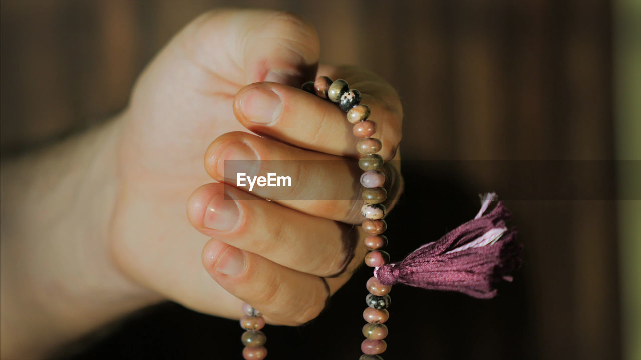 Cropped hand of person holding bead necklace