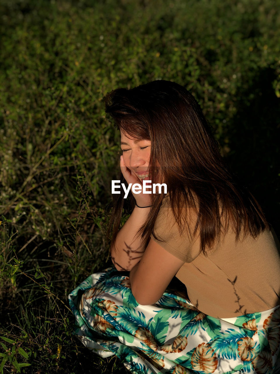 Smiling woman crouching on field