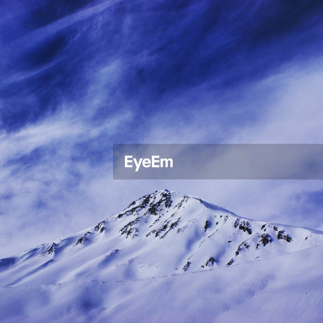 LOW ANGLE VIEW OF SNOWCAPPED MOUNTAINS AGAINST BLUE SKY