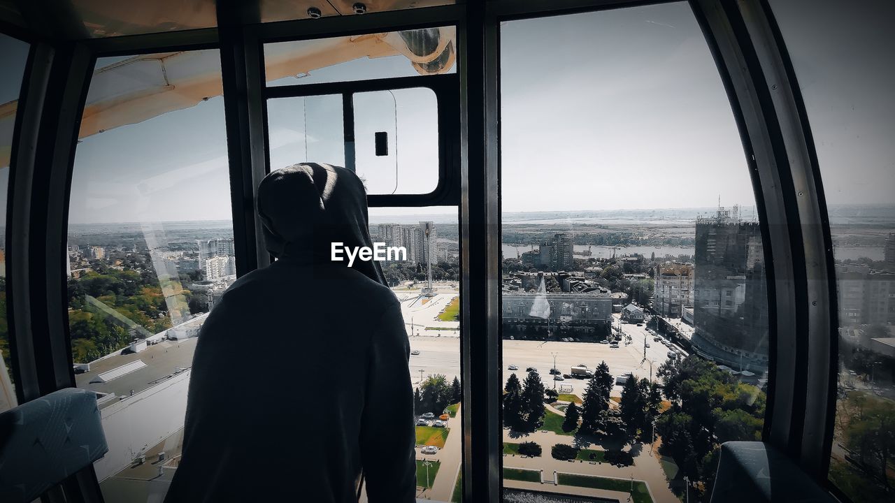 Rear view of man looking through window