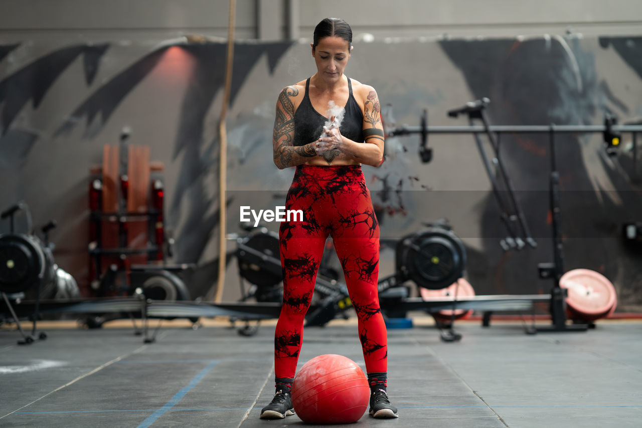 full length of young woman exercising at gym