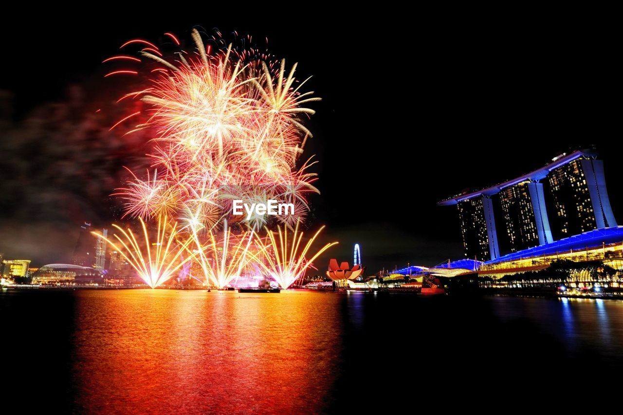 ILLUMINATED FIREWORK DISPLAY OVER RIVER AT NIGHT