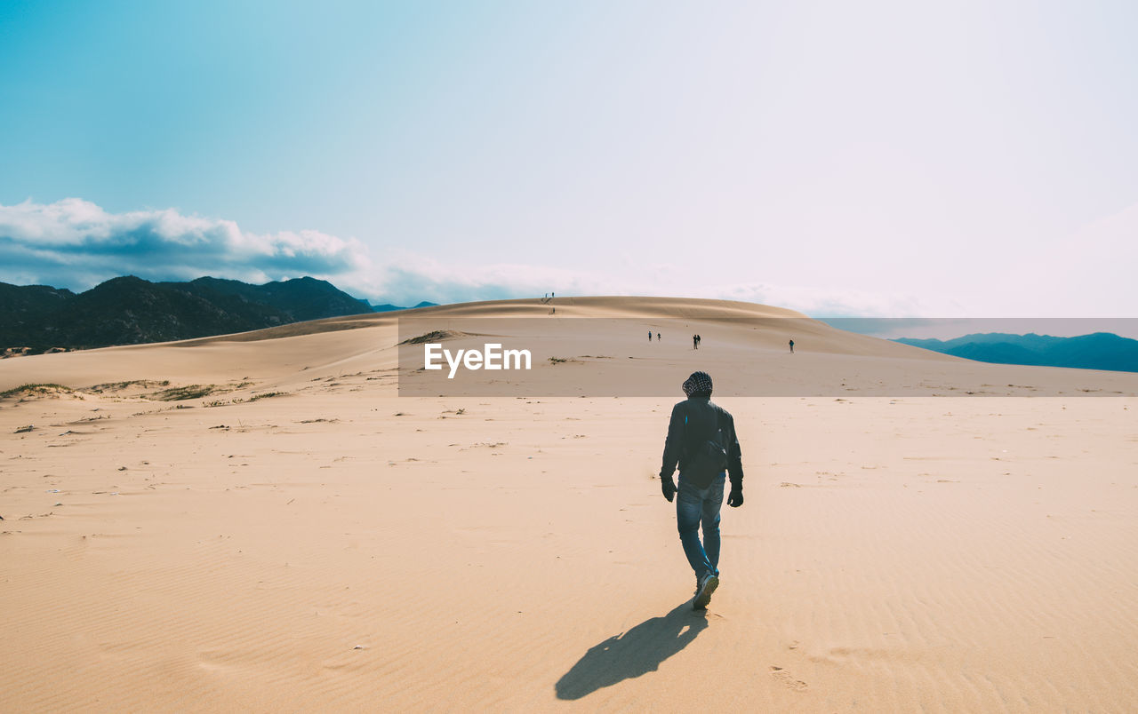 Rear view of man on desert against sky