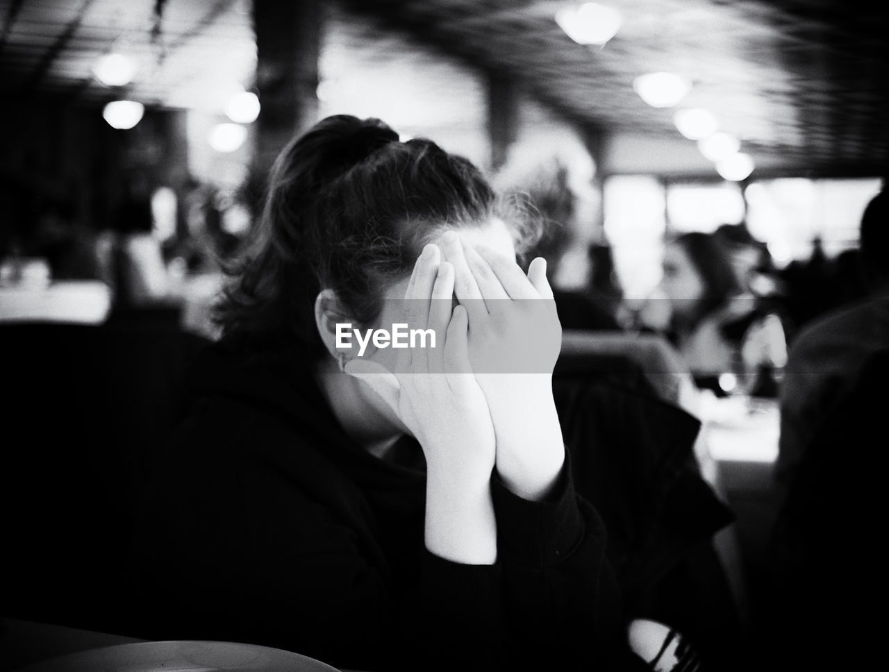 Close-up of girl covering face while sitting at restaurant