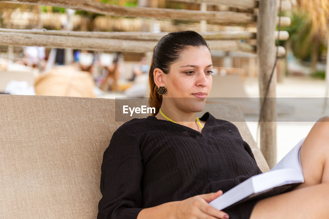 Woman reading book sitting beach