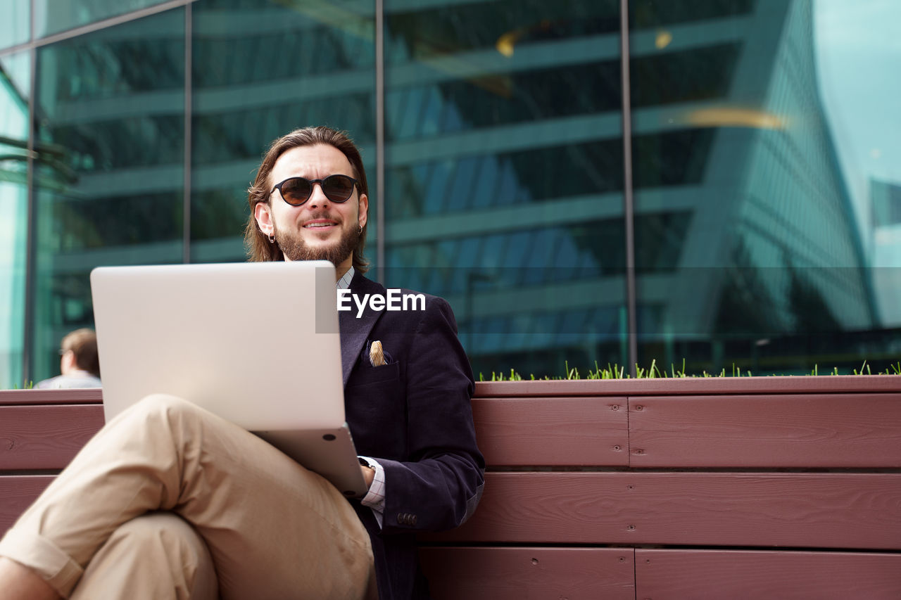 Young man using laptop while sitting on bench