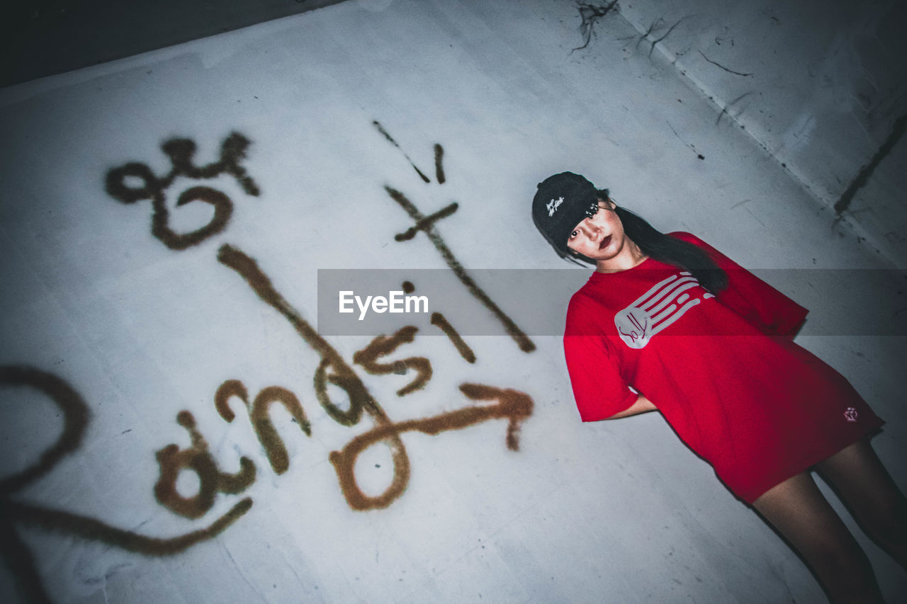 HIGH ANGLE VIEW OF YOUNG WOMAN STANDING BY WALL