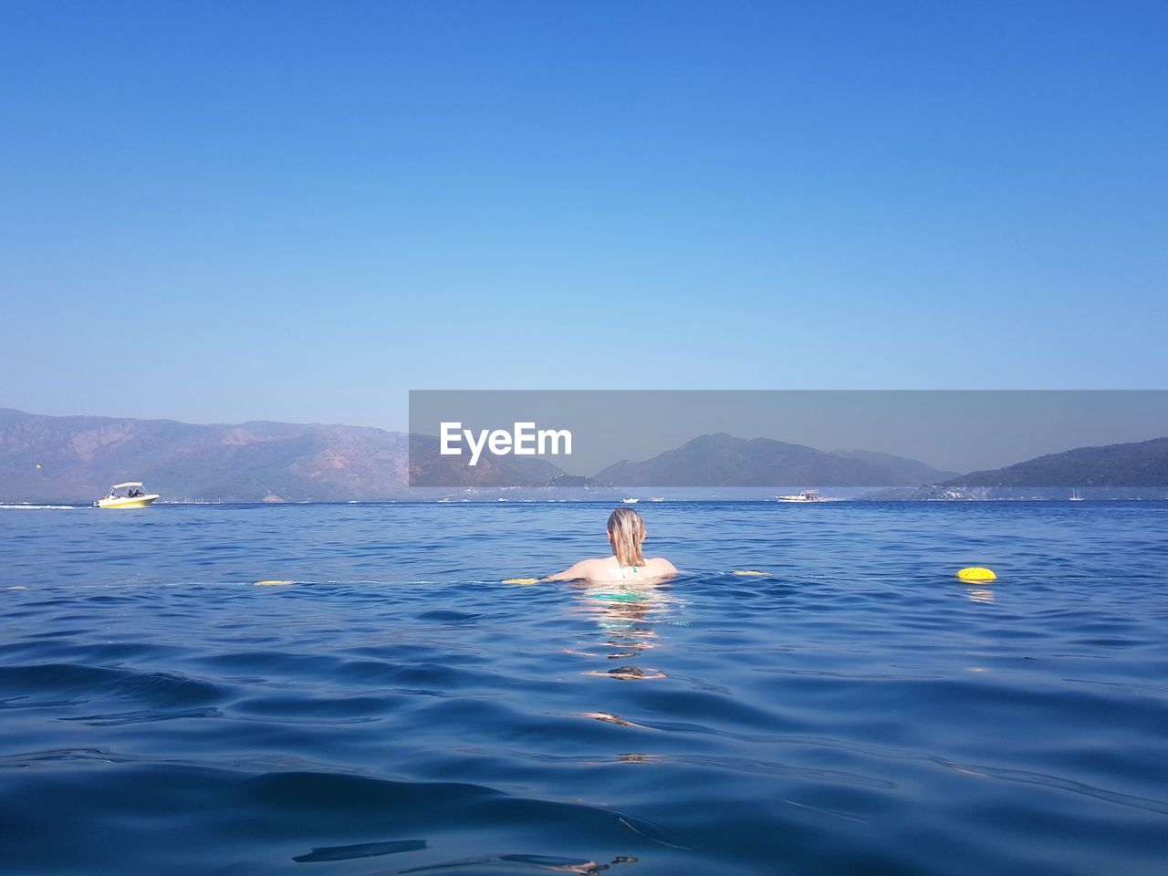 MAN SWIMMING IN SEA AGAINST BLUE SKY