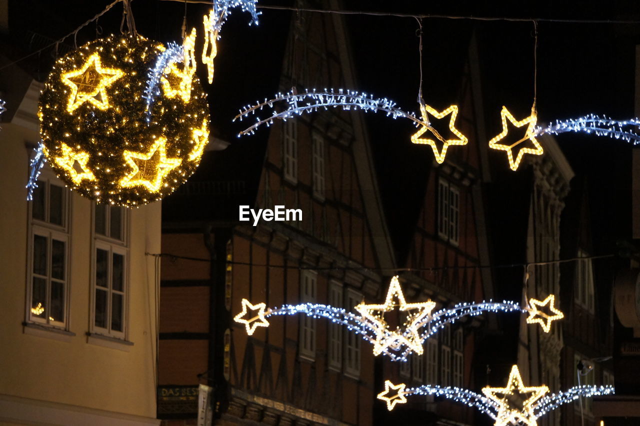 LOW ANGLE VIEW OF ILLUMINATED LANTERNS HANGING ON CHRISTMAS LIGHTS
