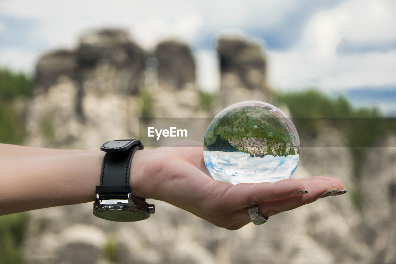 Hand holding crystal ball with upside down image of bastei