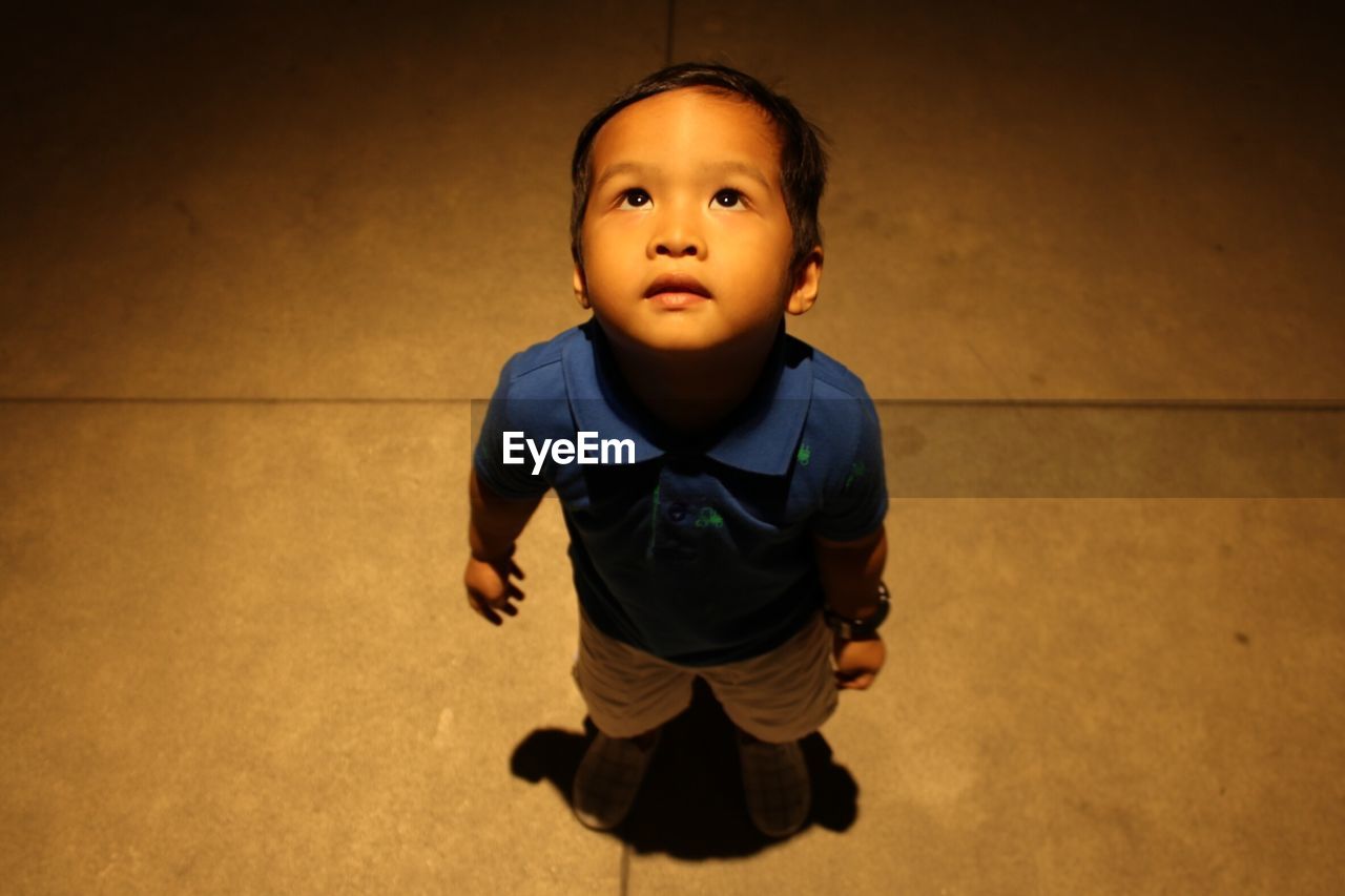 High angle view of boy standing on footpath at night