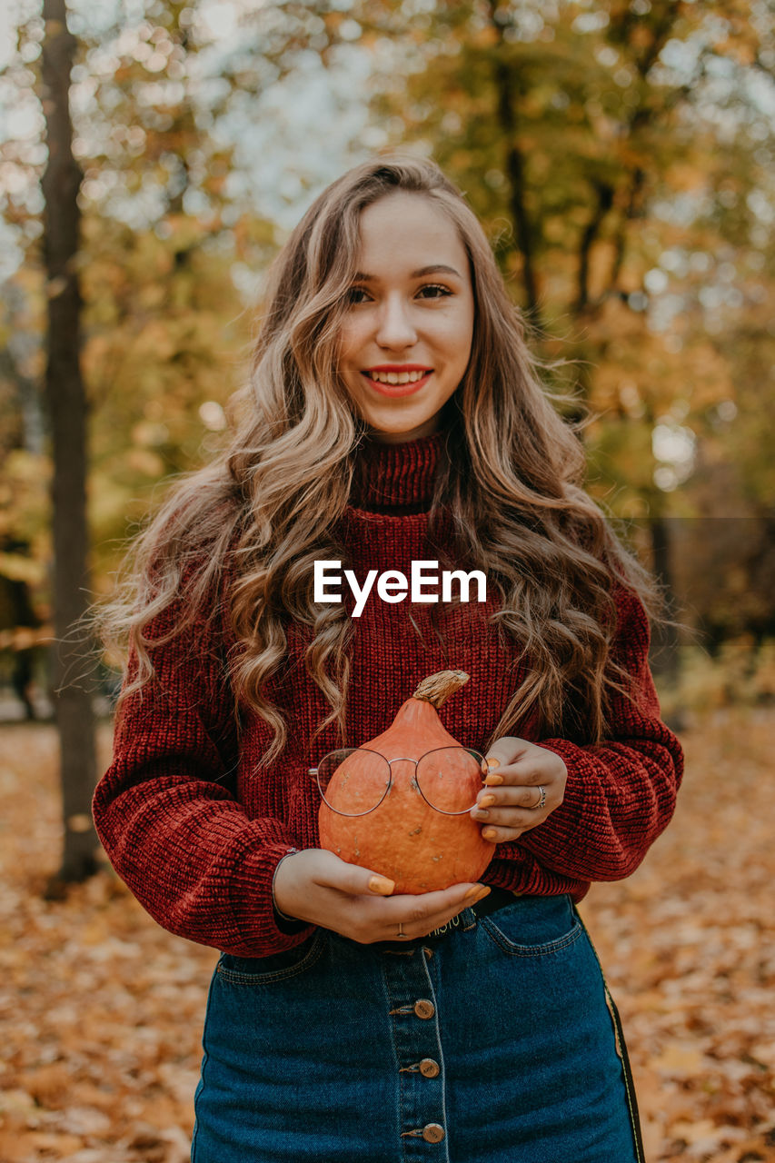 Portrait of smiling young woman standing during autumn