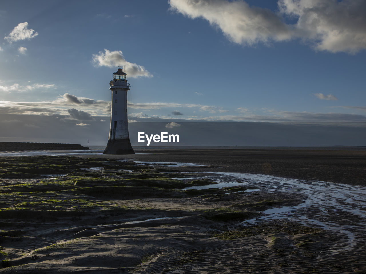 Lighthouse by sea against sky